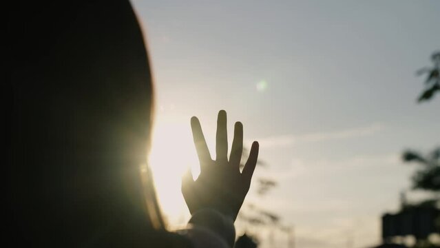 Sunset between hands of girl. Girl dreamily stretches out her hand to sun, rays of sun shine through her fingers. Hand of happy girl reaches for sun. Hand of childs dream to sun. Happy family concept