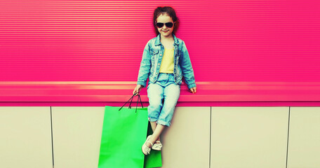 Portrait of little girl child with shopping bags wearing denim clothes on the city street