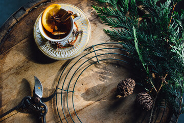 holiday wreath making on a whiskey barrel with a hot toddy in a teacup