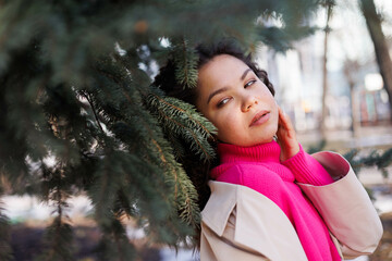 beautiful asia caucasian woman in pink sweater outdoors in street, spring, sun shining. Serious and sad, park trees