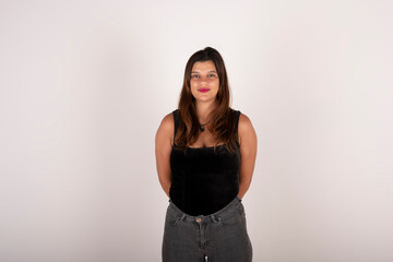 Portrait of a latin woman looking at the camera smiling with hands behind her back and positive attitude on pure background