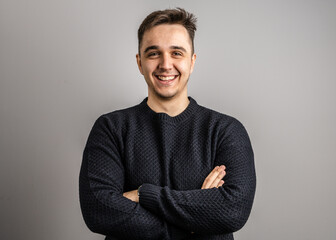 Portrait of one adult caucasian man 25 years old looking to the camera in front of white wall background smiling wearing casual black sweater copy space