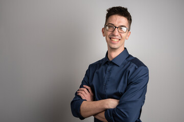 Obraz premium Portrait of one adult caucasian man 25 years old with eyeglasses looking to the camera in front of white wall background smiling wearing casual shirt copy space