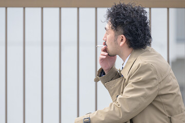 煙草を吸う渋い中年男性　背中