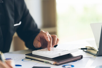 Close up Businessman using calculator and laptop for calaulating finance, tax, accounting, statistics and analytic research concept