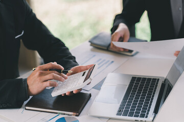 Close up of businessman or accountant hand holding pen working on calculator to calculate business data, accountancy document and laptop computer at office, business concept
