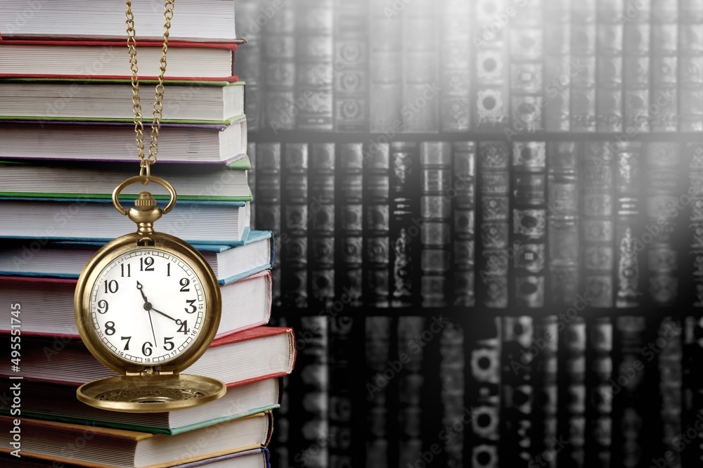 Wall mural old clock on a chain with stack books on library background. retro clock as a symbol of time a books