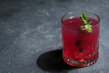 Glass of red berry cocktail decorated mint leaf.