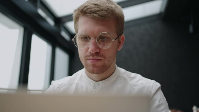 stylish man with glasses for vision is working with laptop, concentrated and serious face
