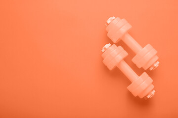 Pair of dumbbells on orange background with space for text
