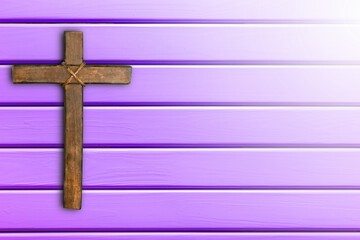 Wooden christian cross on purple background.