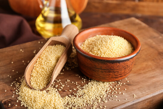 Bowl and scoop with raw couscous on table