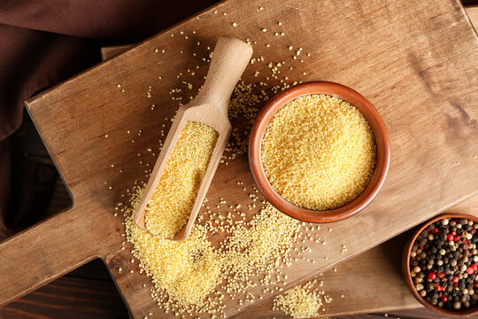 Bowl and scoop with raw couscous and spices on table