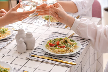Women drinking wine and eating pasta at table, closeup