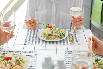 Women eating pasta and drinking wine at table