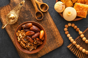 Tasty Eastern sweets with tasbih and Aladdin lamp on dark background