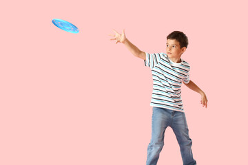 Funny little boy playing frisbee on color background