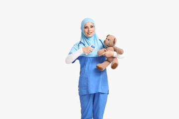 Muslim pediatrician with toy and thermometer on light background