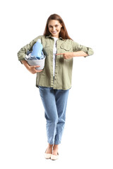 Beautiful woman pointing at small basket with laundry and detergent on white background