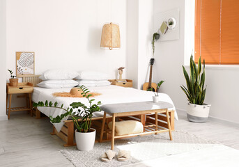 Interior of light bedroom with modern bench and houseplants