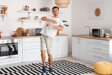 Dancing young man with headphones in kitchen