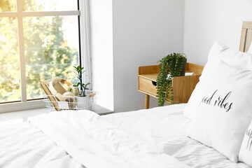 Wooden nightstand with houseplant in light bedroom