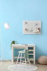 Interior of stylish children's room with desk and hanging pegboard on blue wall