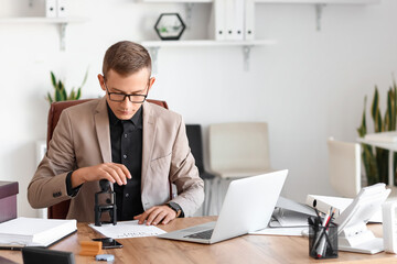 Young male notary public attaching seal to documents in office