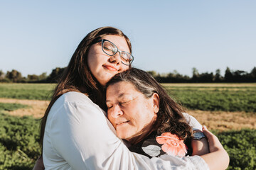 Grandmother and granddaughter hugging in the middle of the field on a sunny day afternoon. Family portrait.