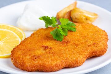 Chicken schnitzel with sauce and lemon in a plate