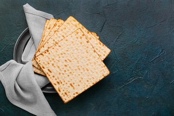 Plate with Jewish flatbread matza for Passover and napkin on dark background