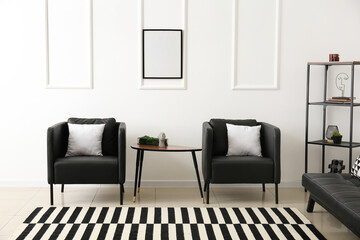 Interior of light living room with black armchairs and table
