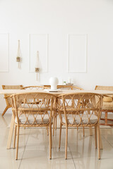 Wooden table with wicker chairs in interior of light dining room