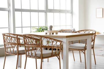 Interior of light dining room with table, sofa and big window