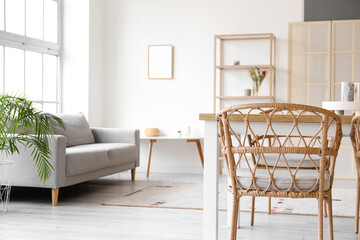Wooden table with wicker chairs in light dining room