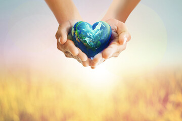 Human Hands holding Earth ball in heart shape on pastel background for World Health Day content and copy space.Elements of this image furnished by NASA - 495557341