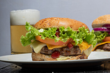 Hamburguesa de carne y queso cheddar con una cerveza de fondo 