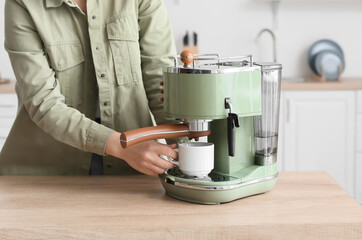 Young woman making tasty coffee in kitchen, closeup