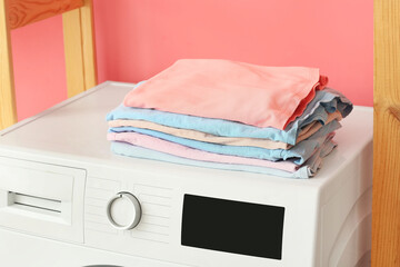 Stack of clean clothes on washing machine in laundry room