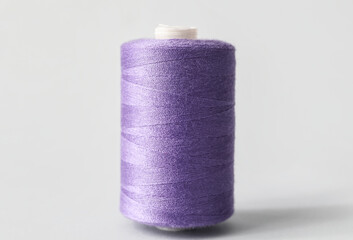 Fototapeta na wymiar Purple sewing thread spool on light background