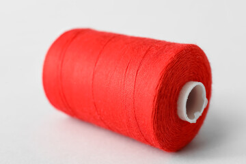 Red sewing thread spool on light background