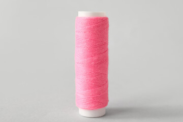 Pink sewing thread spool on light background