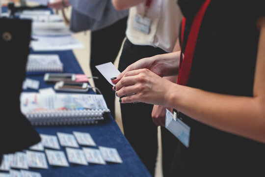 Process of checking in on a conference congress forum event, registration desk table, visitors and attendees receiving a name badge and entrance wristband bracelet and register electronic ticket