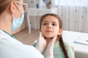 Fototapeta premium Doctor examining little girl's neck in clinic