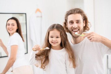 Little girl with her father brushing teeth in bathroom