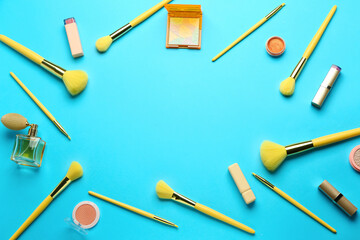 Frame made of makeup brushes and cosmetic products on blue background