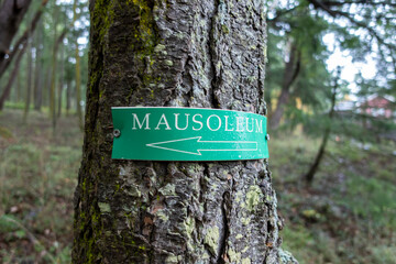 Angled view of a directional arrow sign, pointing the direction to a mausoleum deep in a forested...