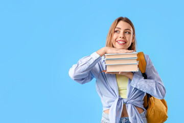 Female student with books on blue background - obrazy, fototapety, plakaty