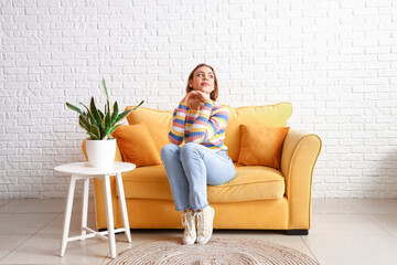 Pretty young woman sitting on sofa at home