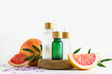 Composition with grapefruit essential oil and fruits on light background